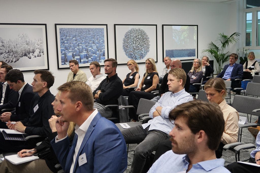 Image showing 14 companies attentively listening to speakers at an event.